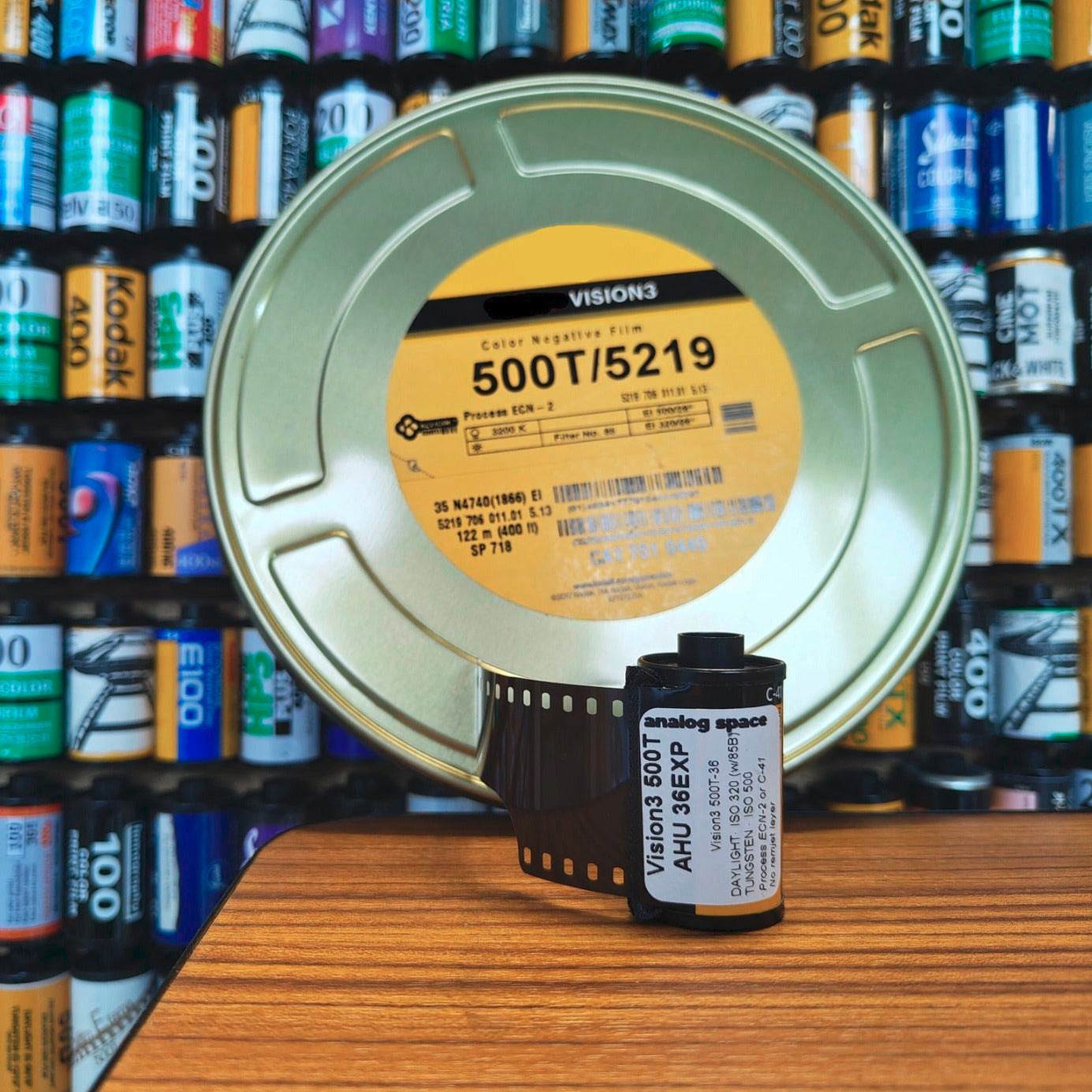 Roll of 35mm Vision3 film with a 122m reel can of said film in the background
